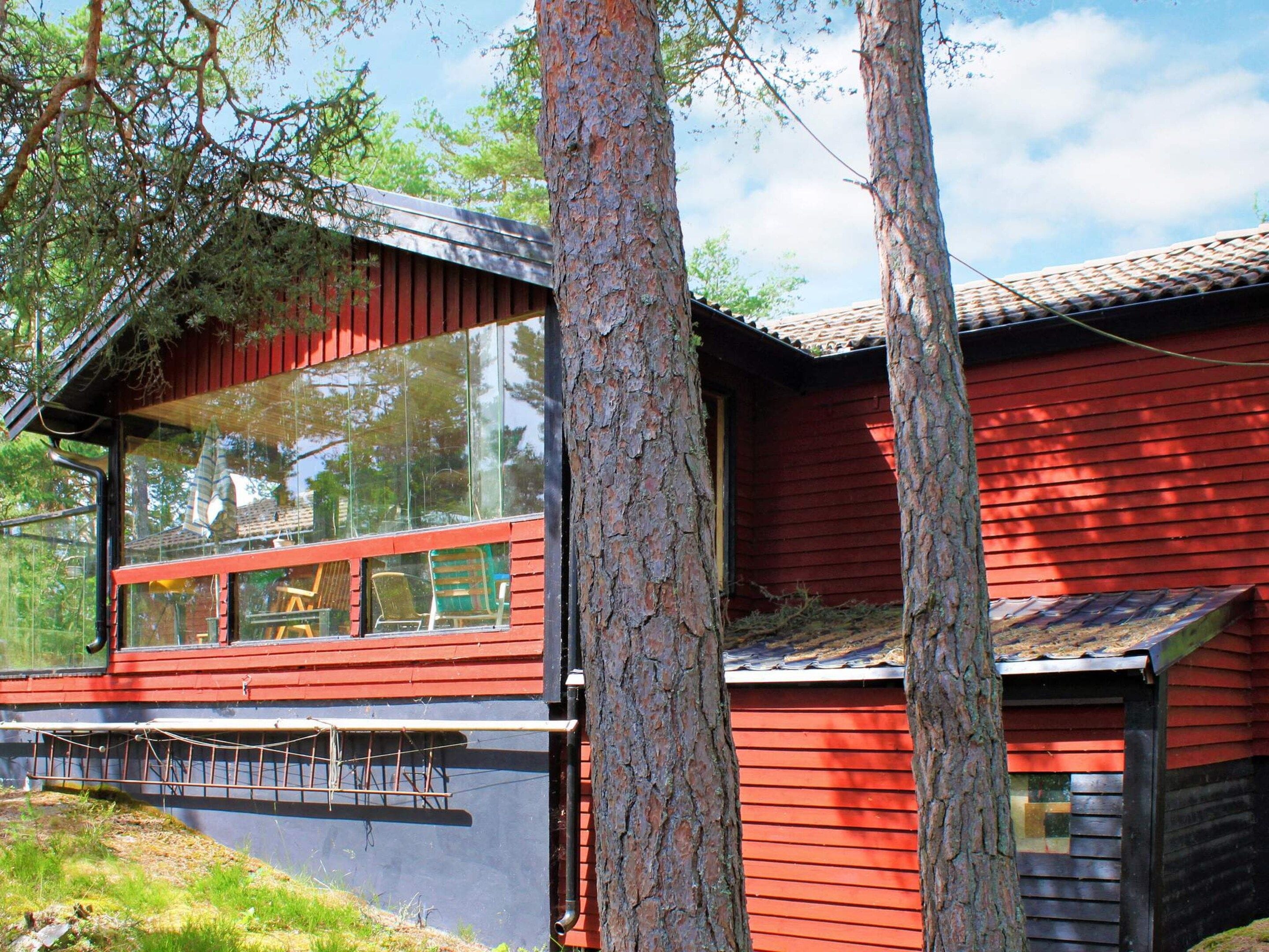 A modern red wooden cabin with a large glass window and a metal roof.