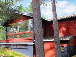 A modern red wooden cabin with a large glass window and a metal roof. - 6 Person Holiday Home in Lidkoping (Lidköping)