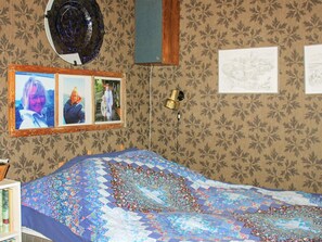 A bedroom with a bed, a wall-mounted lamp, and a framed photo collage.