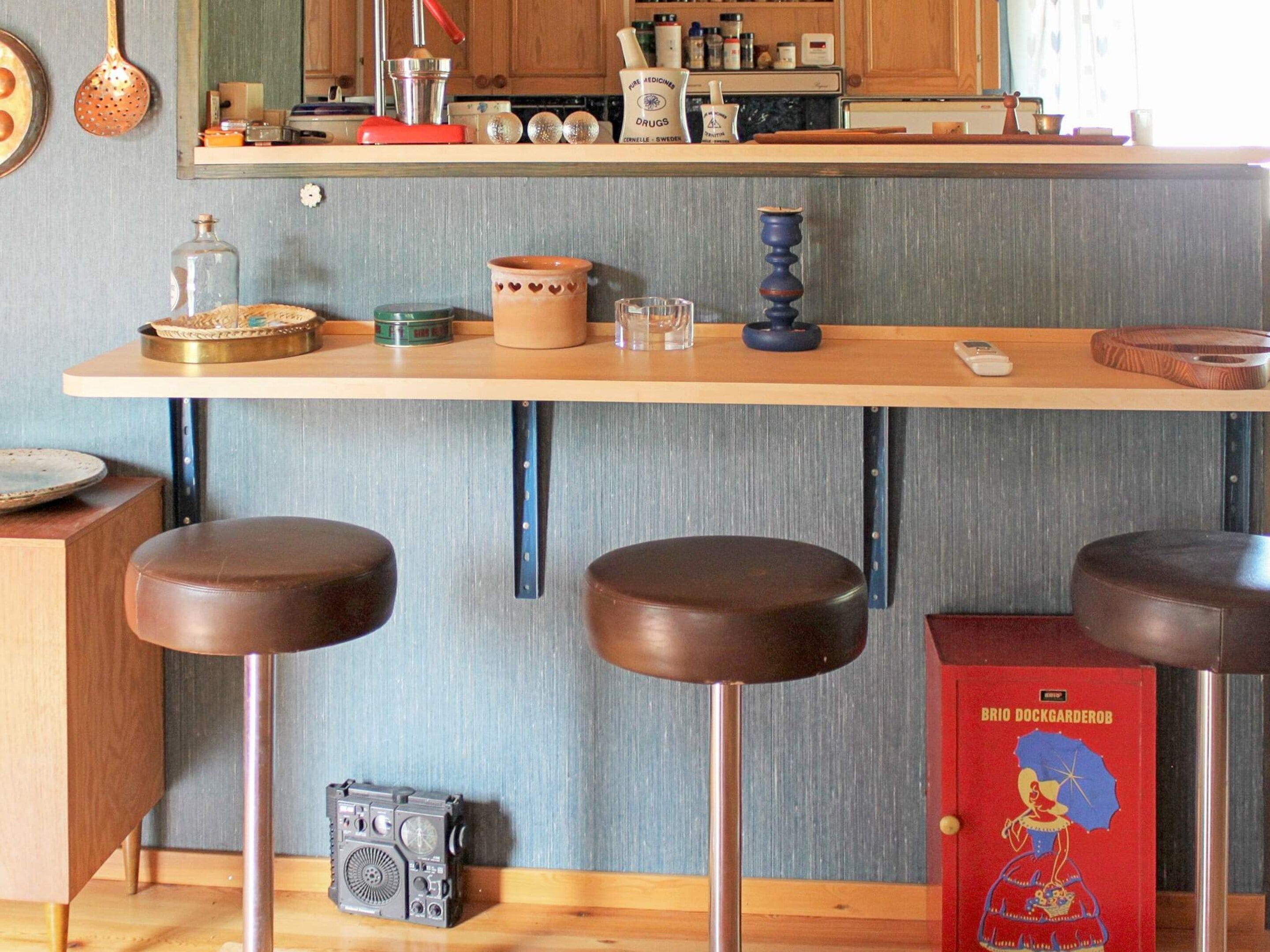 A kitchen with a wooden countertop, stools, and a vintage radio.