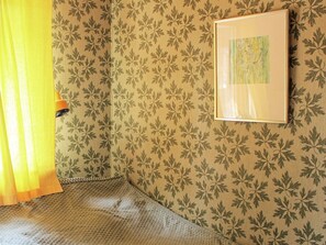 A room with patterned wallpaper, a framed picture on the wall, and a yellow curtain partially drawn. - 6 Person Holiday Home in Lidkoping (Lidköping)