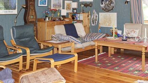A cozy living room with wooden furniture, a clock, and various framed artworks on the walls. - 6 Person Holiday Home in Lidkoping (Lidköping)