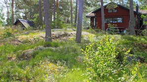 A red cabin surrounded by forest, with a smaller structure nearby. - 6 Person Holiday Home in Lidkoping (Lidköping)