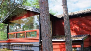 A modern red wooden cabin with large windows and a balcony. - 6 Person Holiday Home in Lidkoping (Lidköping)
