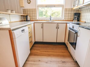 A compact kitchen with a dishwasher, oven, and coffee maker.