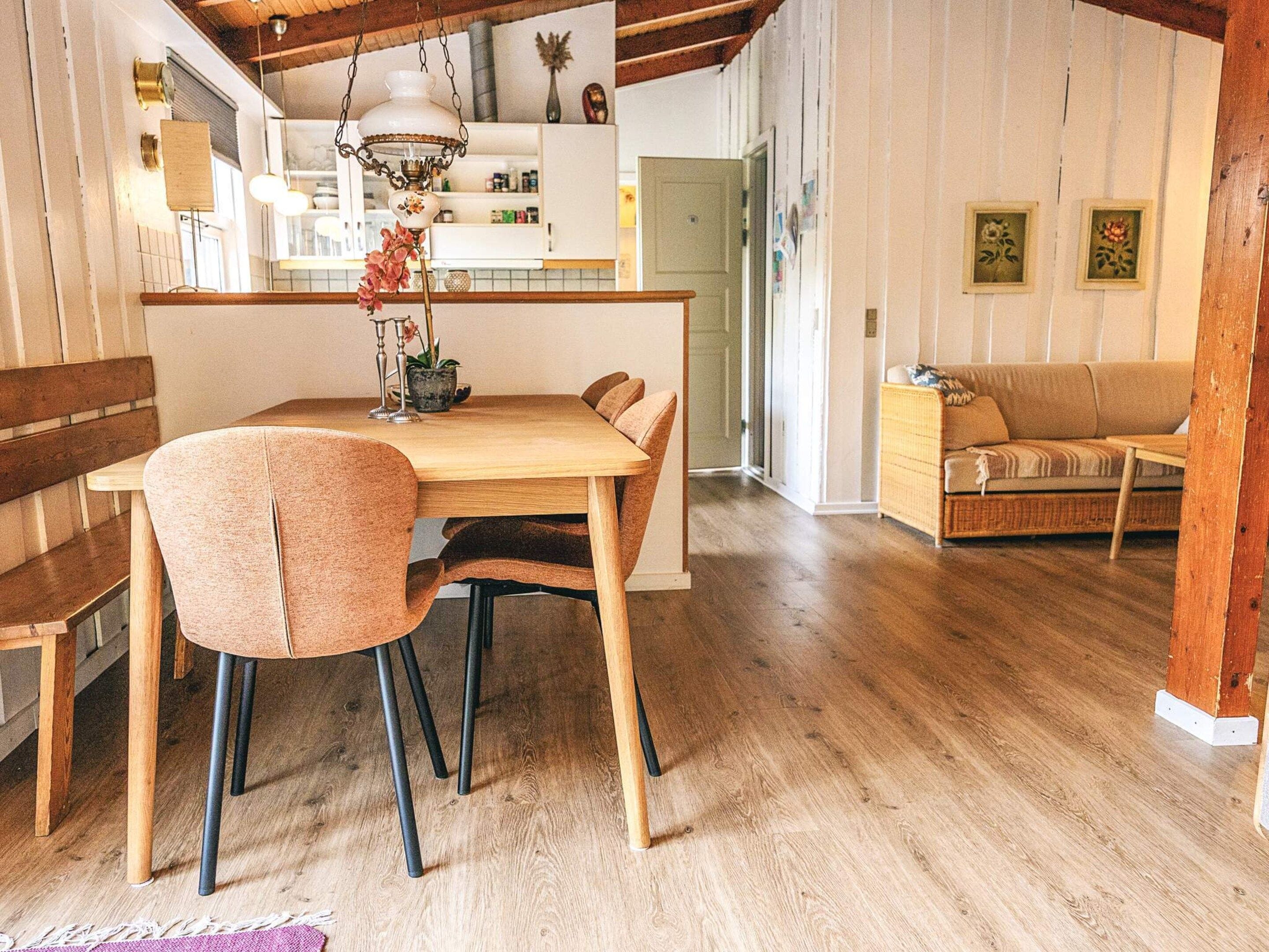 Ein Essbereich mit Holztisch und Stühlen, einer Hängelampe und einer Küche im Hintergrund.