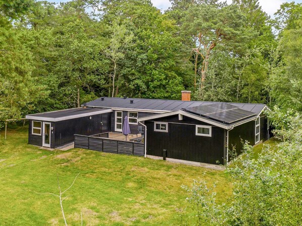 A modern house with a large deck, solar panels, and surrounded by dense trees. - 4 Star Holiday Home in Hadsund (Hadsund)