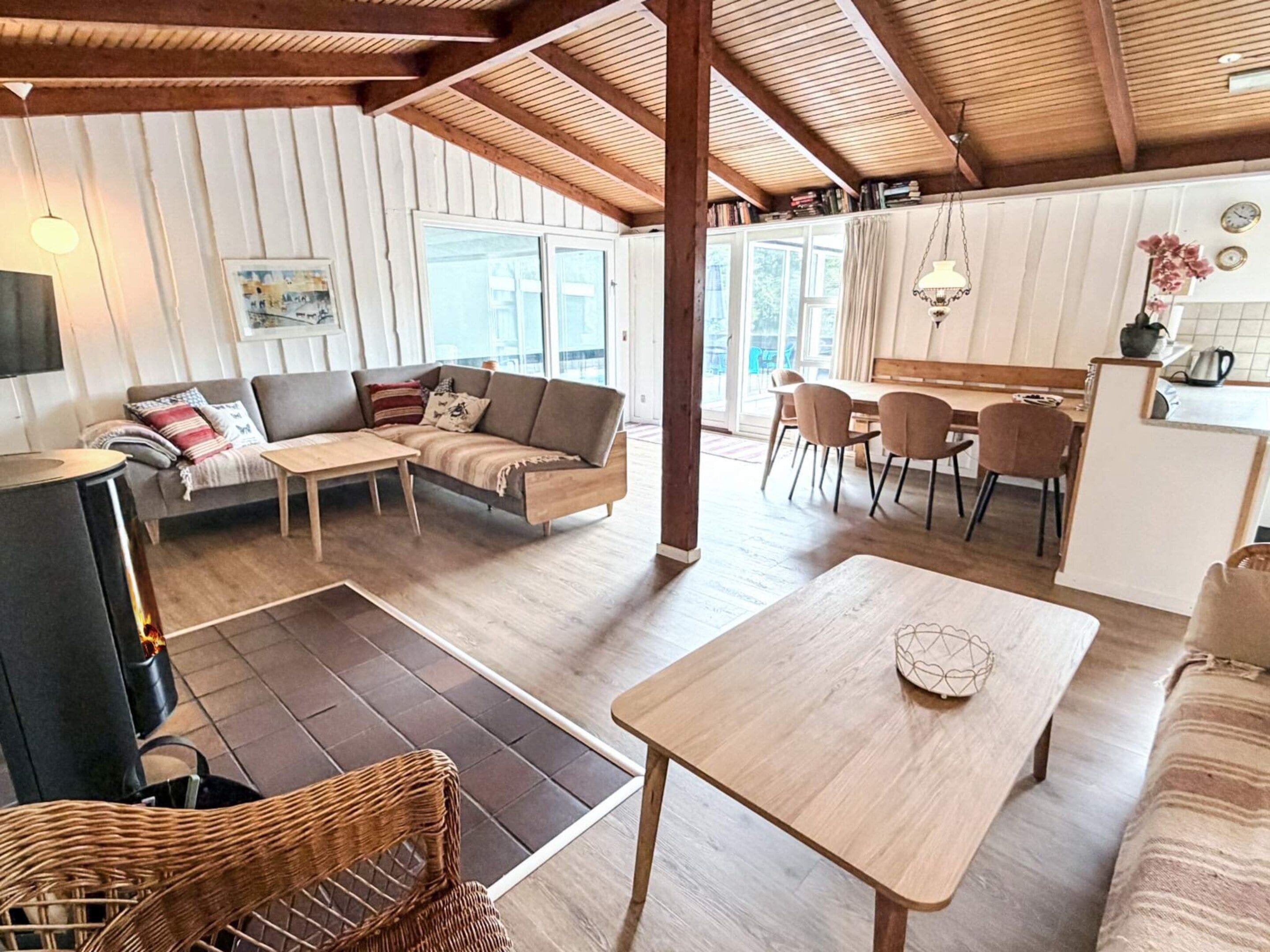 En rummelig opholdsstue med sofa, spisebord og et køkken i baggrunden.