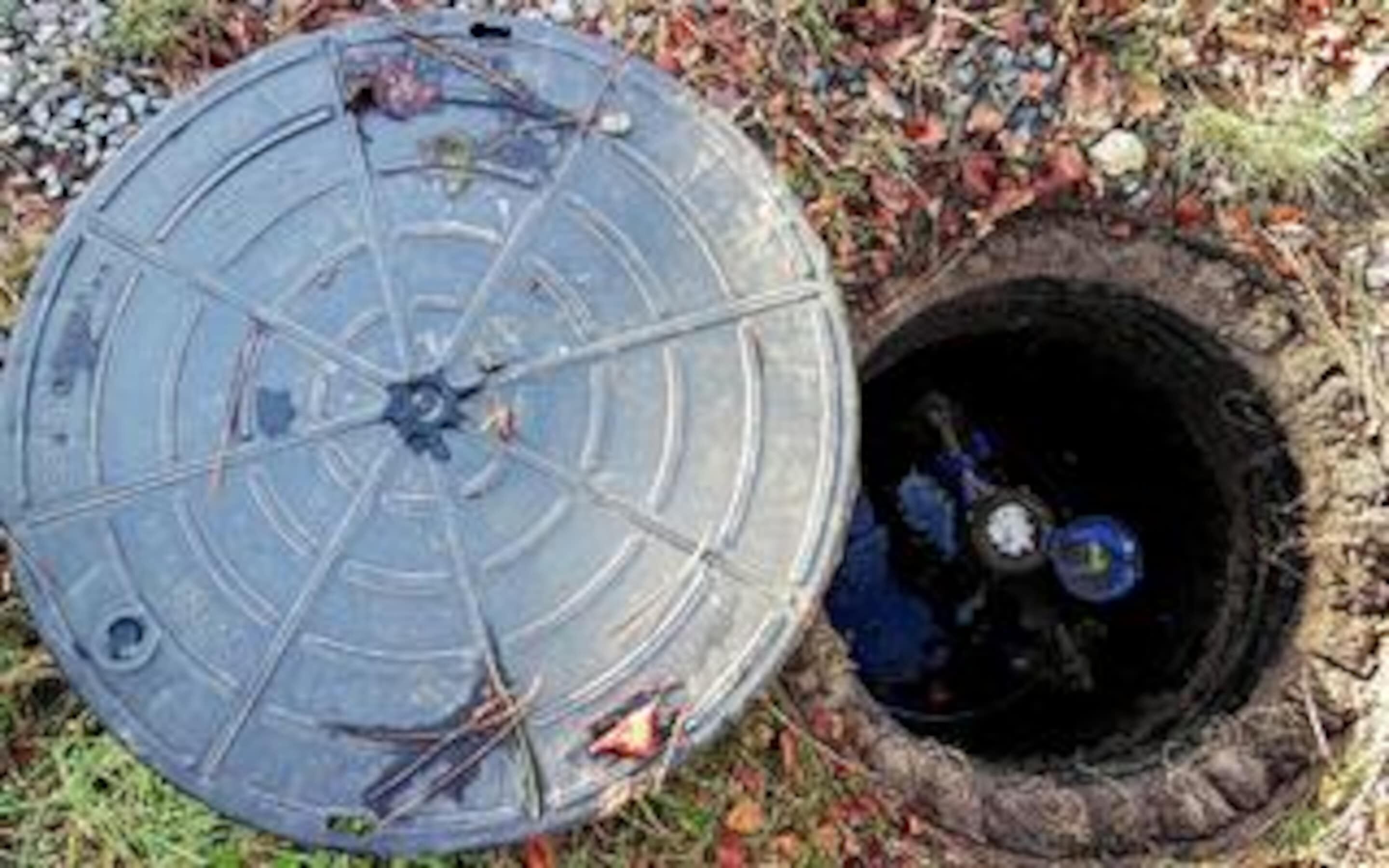 A manhole cover with a circular design and a metal pipe extending from it.