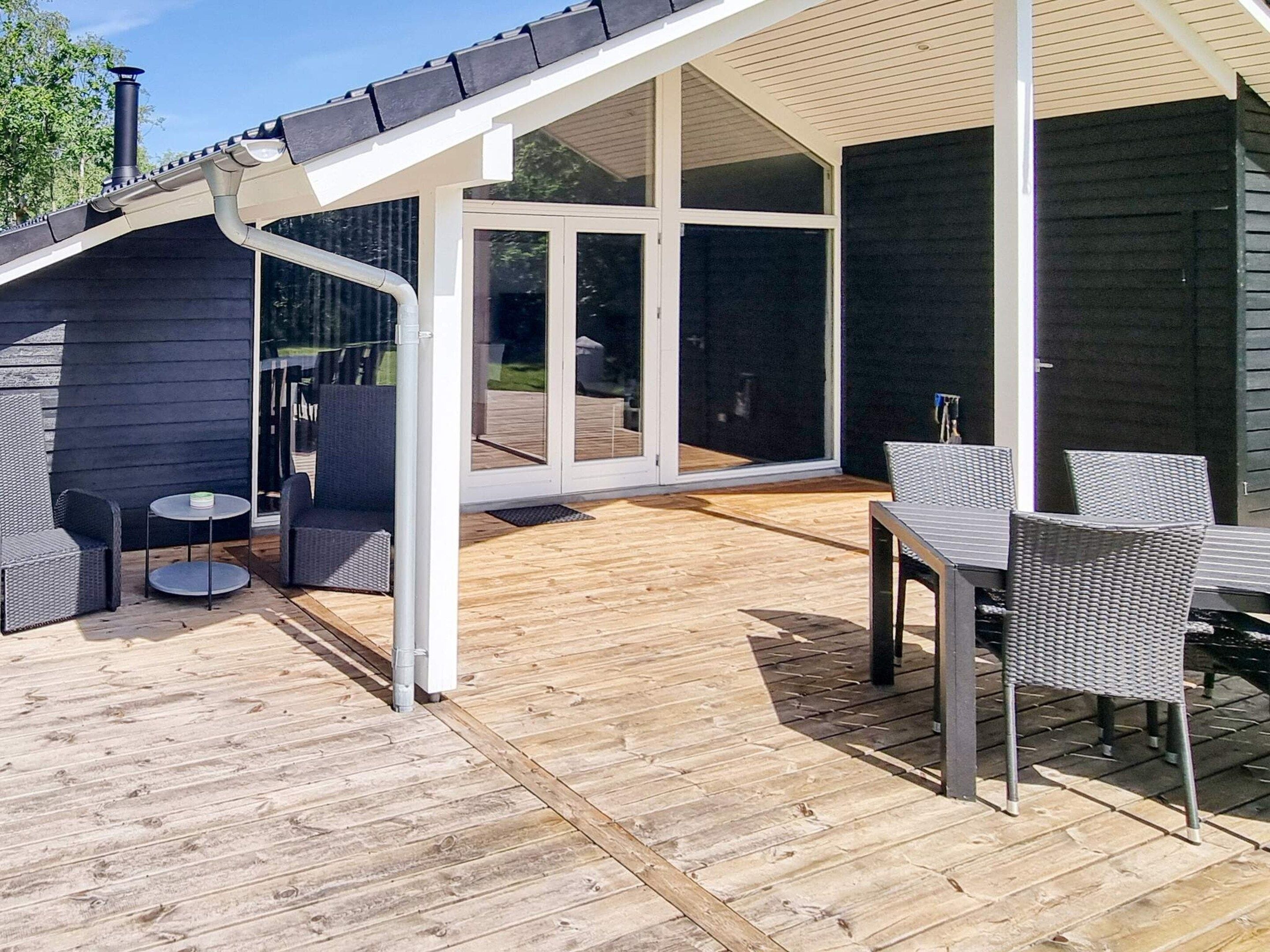 An outdoor patio with a wooden deck, a covered seating area, and a glass door leading to an interior space.