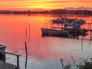 A calm lake at sunset with boats docked at a pier.