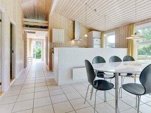 A modern kitchen with a central island, white cabinets, and a dining area with a round table and black chairs. - 4 Star Holiday Home in Albaek (Aalbaek)