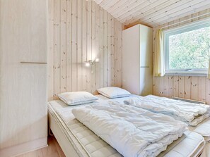 A bedroom with a bed, a wardrobe, a window, and a wall-mounted light fixture. - 8 Person Holiday Home in Albaek (Aalbaek)