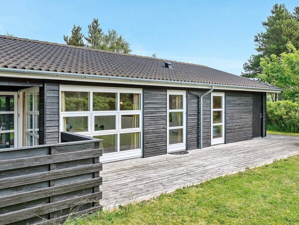 A modern building with large windows, a wooden deck, and a grey exterior.