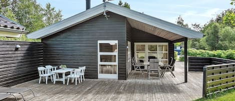 A wooden deck with a covered patio area, a white door, and a satellite dish on the roof.