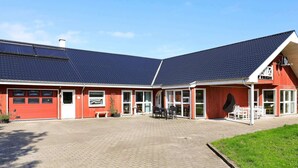 Ein rotes Gebäude mit einem Ziegeldach, großen Fenstern und einem gepflasterten Innenhof.