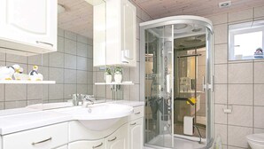 Ein modernes Badezimmer mit einer in Glas eingefassten Dusche, einem weißen Waschtisch mit Spüle und einer Toilette.