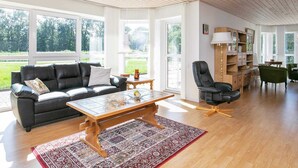 Ein geräumiges Wohnzimmer mit einer schwarzen Ledersofa, einem Holztisch und einem gemusterten Teppich.