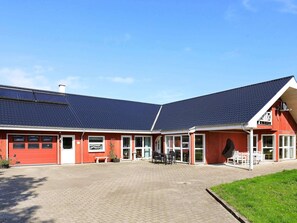 A red building with a tiled roof, large windows, and a paved courtyard.