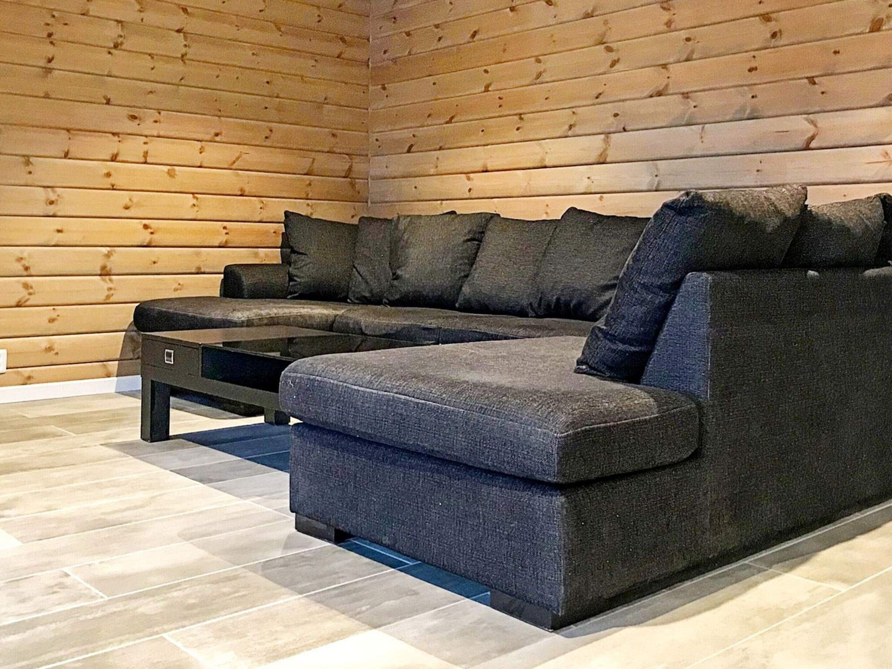 A modern living room with a sectional sofa, a coffee table, and a wooden wall.