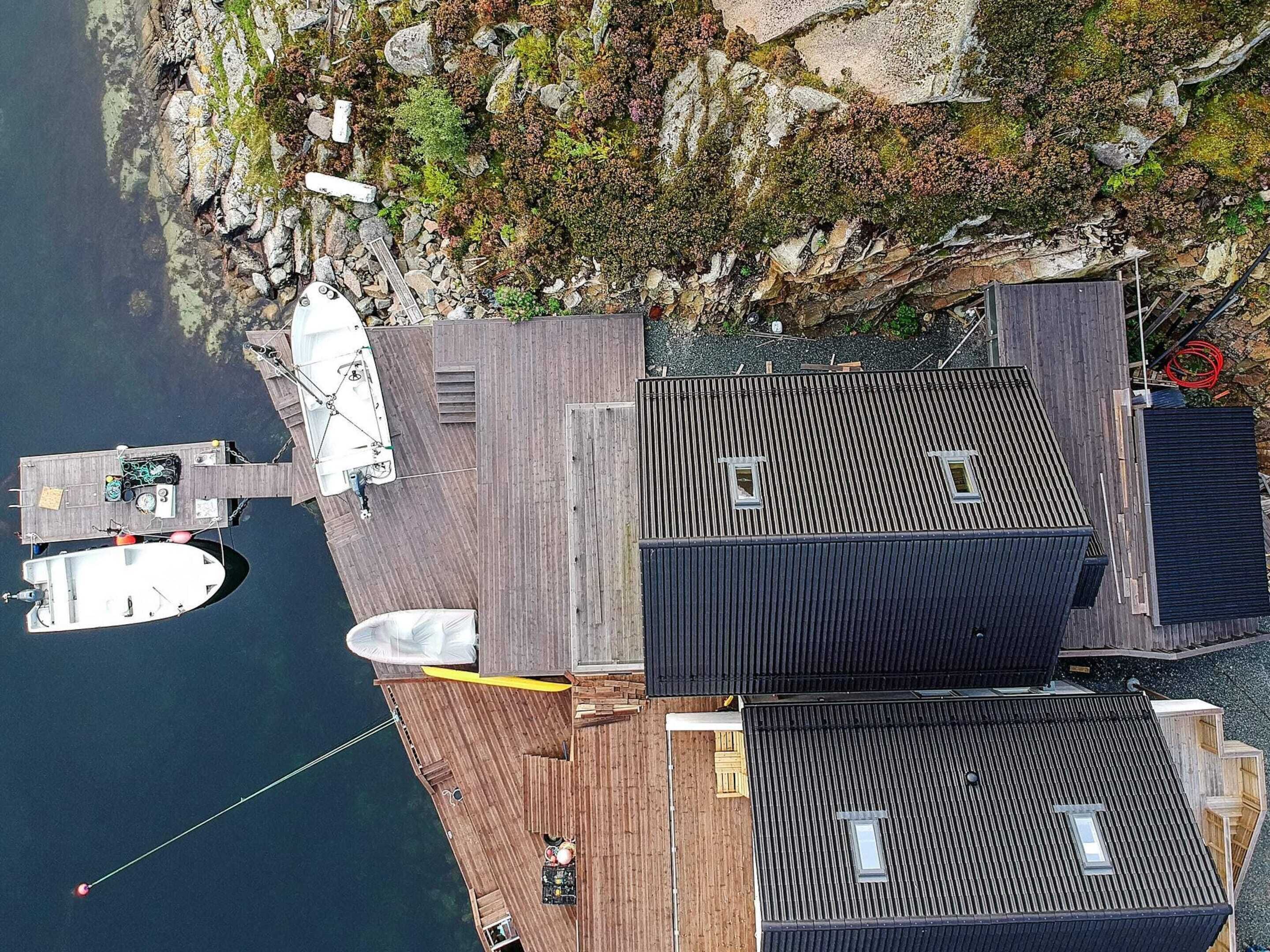 A dock with a boat, a wooden deck, and a building with a sloped roof.