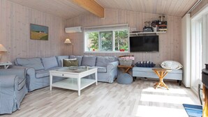 Un salon chaleureux avec un canapé à rayures, une table basse en verre et un téléviseur fixé au mur.