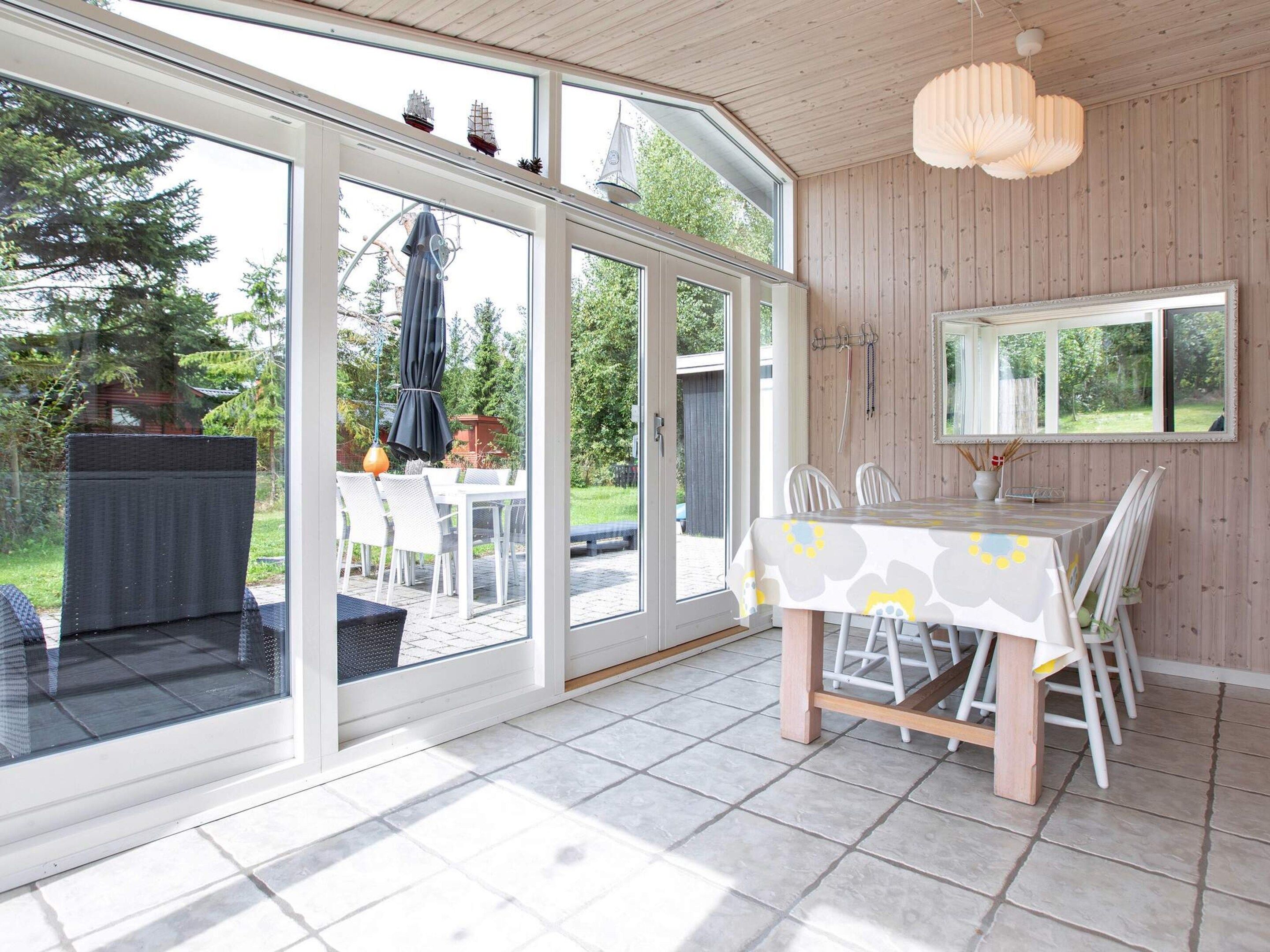 A dining area with a table set for four, large windows, and a view of the outdoors.