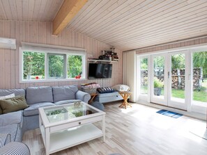 A cozy living room with a striped sofa, a glass coffee table, and a TV mounted on the wall.