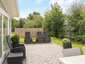 An outdoor patio with wicker furniture, a table, and a lamp post. - 4 Star Holiday Home in Hojby (Hojby)
