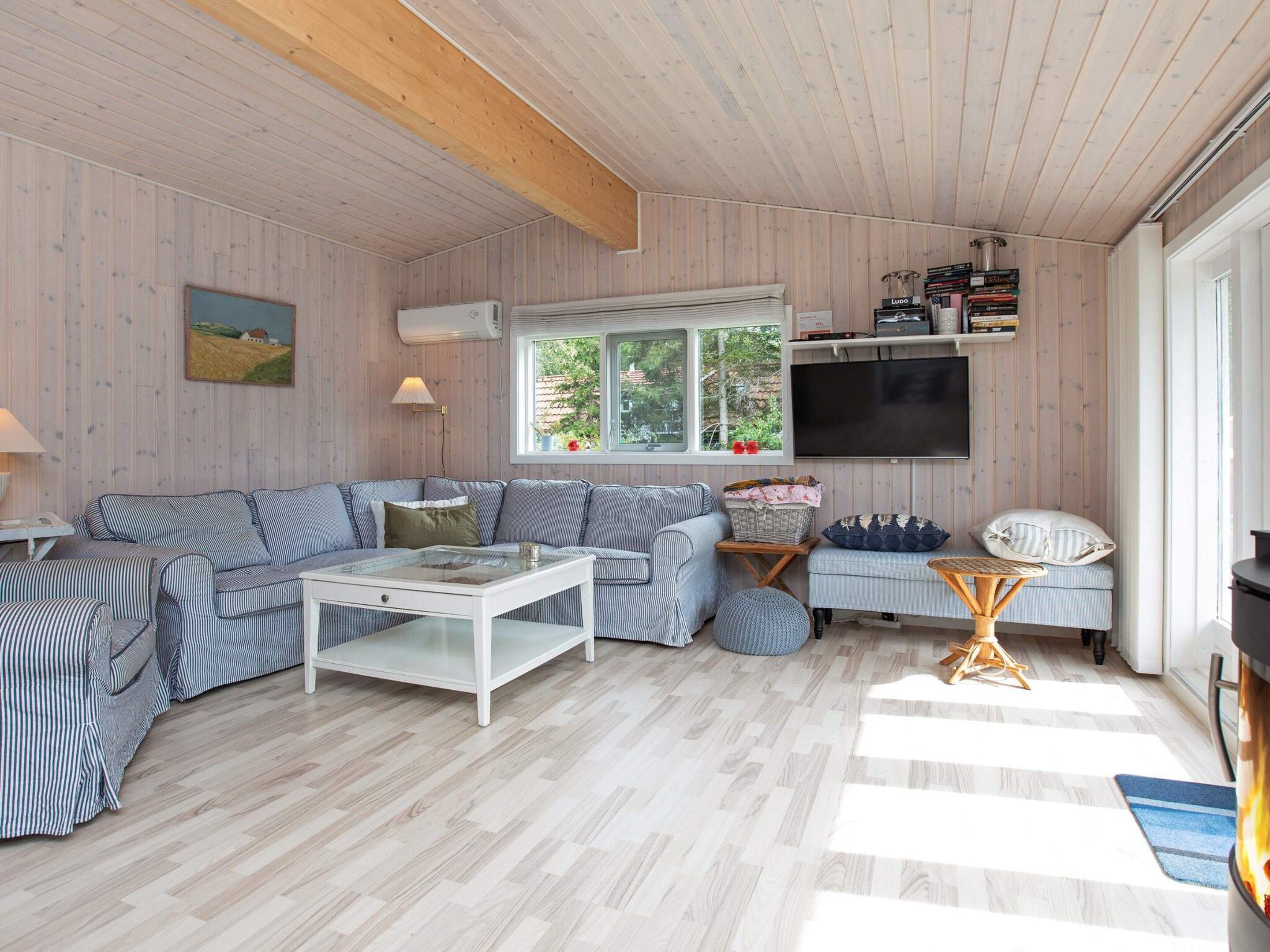 A cozy living room with a sectional sofa, a coffee table, and a TV mounted on the wall.
