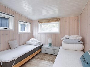 A bedroom with two single beds, a nightstand, a lamp, and a window with a curtain. - 4 Star Holiday Home in Hojby (Hojby)