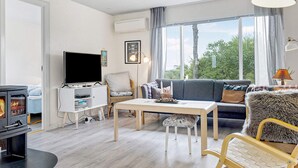 A modern living room with a fireplace, a sofa, a TV, and a dining area. - 6 Person Holiday Home in Saeby (Sæby)