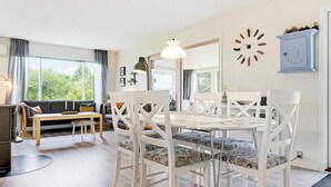 A modern living room with a round dining table, white chairs, and a sofa. - 6 Person Holiday Home in Saeby (Sæby)