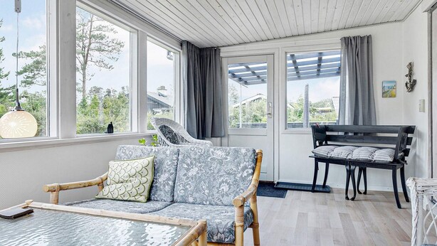 A cozy room with a wooden ceiling, large windows, a sofa, a table, and a bench. - 6 Person Holiday Home in Saeby (Sæby)