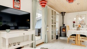 A modern living room with a flat-screen TV, a fireplace, and a dining area with wooden chairs and a table. - 6 Person Holiday Home in Rodby (Rodby)