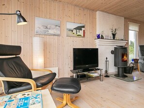 A cozy living room with a television, a fireplace, wooden walls, and a comfortable seating area.