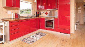 Une cuisine moderne avec des meubles rouges et un plafond en bois.