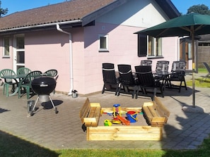 A patio area with a barbecue grill, outdoor seating, and a play area with toys.