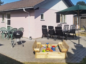 A patio with a grill, chairs, and a table. - 5 Person Holiday Home in Vaeggerlose (Vaeggerlose)