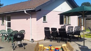 A patio with a barbecue grill, outdoor seating, and a play area with toys. - 4 Star Holiday Home in Vaeggerlose (Vaeggerlose)
