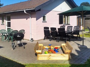 A patio with a barbecue grill, outdoor seating, and a play area with toys. - 4 Star Holiday Home in Vaeggerlose (Vaeggerlose)