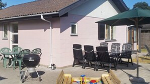 A patio with a grill, chairs, and a table. - 4 Star Holiday Home in Vaeggerlose (Vaeggerlose)