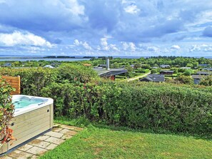 A residential area with a hot tub, a pathway, and houses with a view of a lake and distant land.