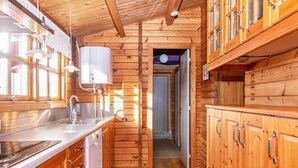 A wooden cabin interior with a kitchen area, wooden walls, and a hallway leading to another room. - 6 Person Holiday Home in Lemvig (Lemvig)