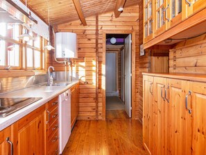 A wooden cabin interior with a kitchen area, including a sink, cabinets, and a window. - 6 Person Holiday Home in Lemvig (Lemvig)