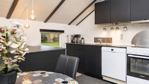 A modern kitchen with black cabinets, a white dishwasher, and a stainless steel stove. - Scenic Fjord Retreat-by Traum (Vemb)