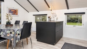 A modern kitchen with a black island, white walls, and a wooden ceiling. - Scenic Fjord Retreat-by Traum (Vemb)