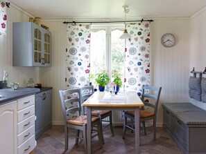 A kitchen with a dining table, chairs, cabinets, and a clock on the wall.