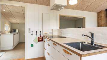 Una cocina moderna con armarios blancos, un lavamanos negro y una encimera de madera.