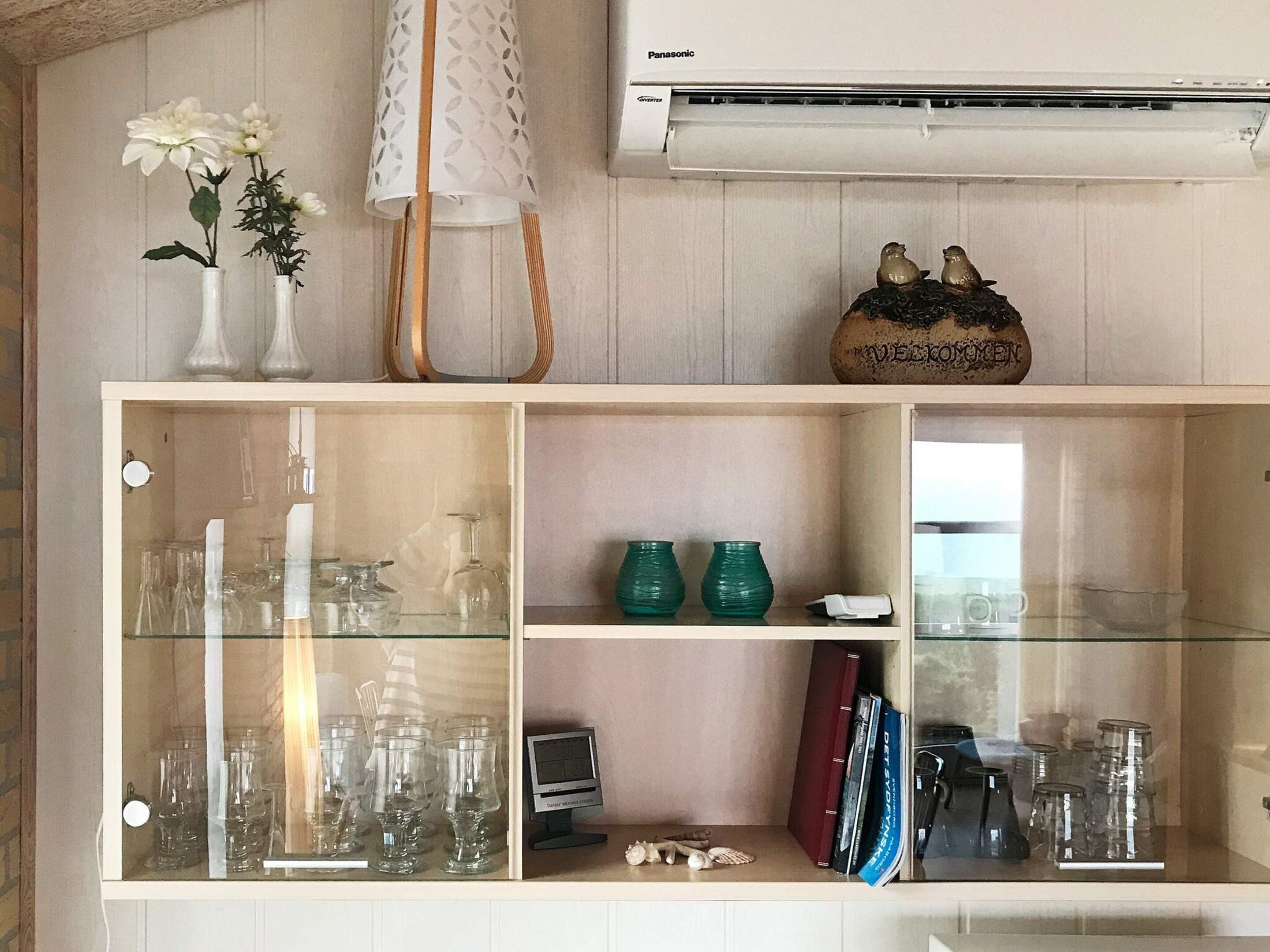Ein Zimmer mit einer Glaskabine, die verschiedene Gläser sowie einen kleinen Fernseher beherbergt.
